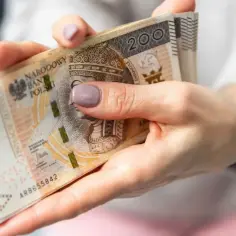 Dłonie trzymają plik banknotów 200 zł. Czy praca w porze nocnej dodatek do wynagrodzenia ile realnie wynosi?