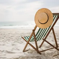 Pusta leżanka z kapeluszem na plaży, symbolizująca wczasy pod gruszą i świadczenia z ZFŚS dla pracowników.