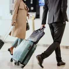 Mobilny pracownik handlowiec w podróży służbowej, ciągnie walizkę.