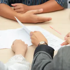 Próbne zadania rekrutacyjne w domu czy za projekt należy się zapłata. Dwie osoby analizują dokumenty, jedna wskazuje palcem na tekst.