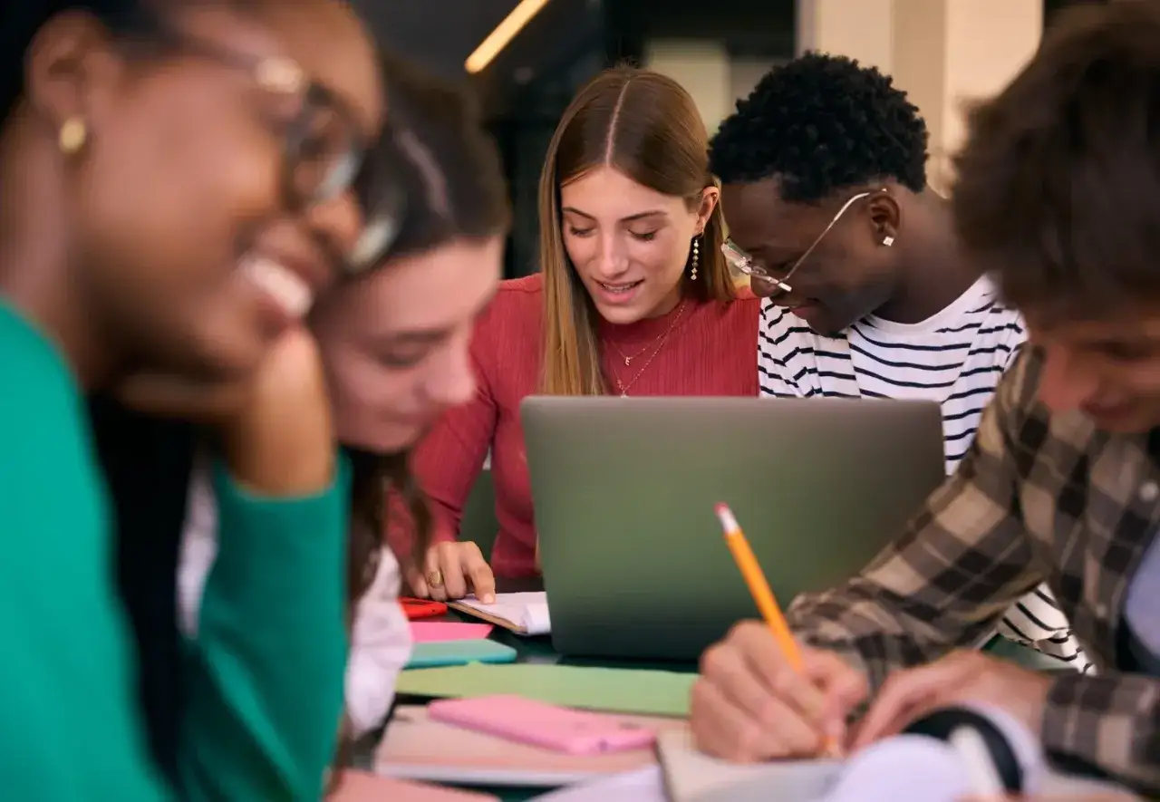 Studenci przy laptopie, dyskutują o stażu z urzędu pracy a studiach dziennych, aktualnych ograniczeniach wiekowych i prawnych.
